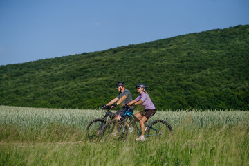 Fototapeta premium Side view of senior couple exploring nature on electric bicycles