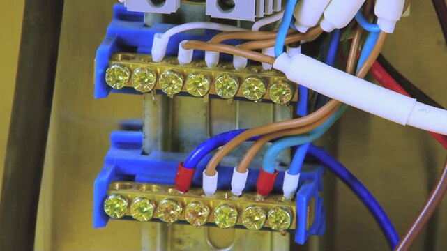 Close view of electrical panel's heart, where diverse wires meticulously join golden terminals. Blue blocks organize essential network, enabling seamless power distribution for home or facility.