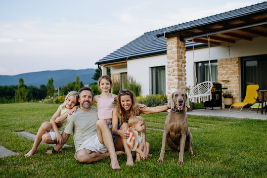 Parents and daughters enjoying late summer together outside family home.