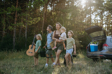 Naklejka premium Family preparing for outdoor camping trip after traveling by car.