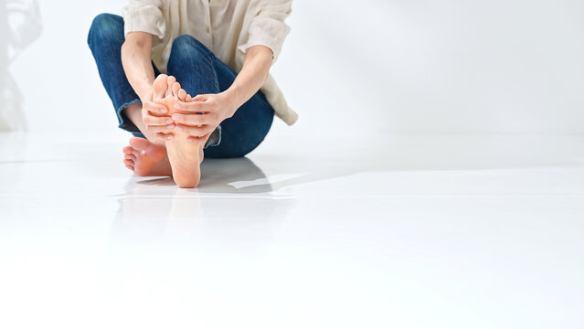 A woman massaging the soles of her feet. Massage, foot care, acupoints, corns, calluses, warts, athlete's foot, arch, plantar fasciitis, flat feet.