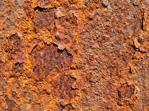 A close-up texture of heavily oxidized and rusted metal surface with flaky iron oxide patches and orange corrosion patterns