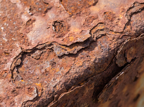 Macro shot of heavily rusted metal surface showing flaky corrosion, texture, and decay