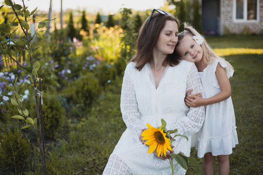 a cute five-year-old girl with mother in a white dress are playing in a green summer garden. happy childhood
