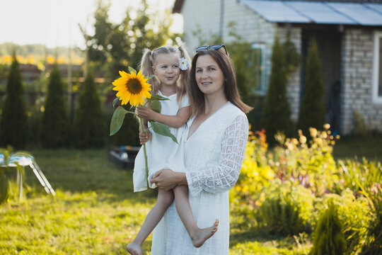 a cute five-year-old girl with mother in a white dress are playing in a green summer garden. happy childhood