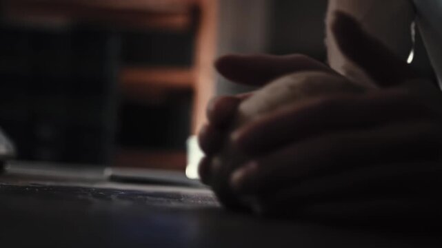 Male hands shaping raw dough on table preparing fresh bread and rolls. Bakery environment, food preparation process, baking production, artisan skill. Close up view