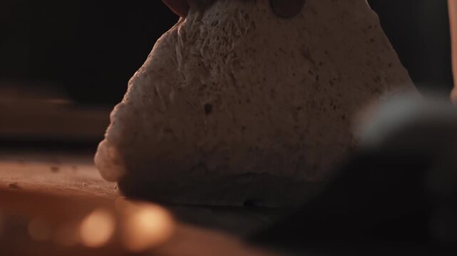 Baker hands shaping dough for artisanal bread and rolls in small bakery. Preparation process on wooden surface. Food production and craft work concept. Close up detail