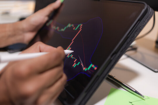 Professional stock trader reviewing market charts with sticky notes across multiple monitors, laptop, and tablet to analyze price trends, plan trading strategies, and manage investment decisions.