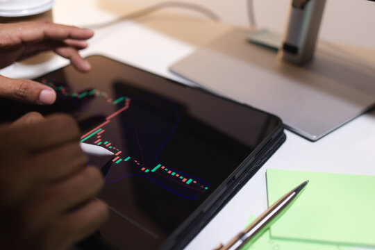 Professional trader analyzing stock market charts on laptop, tablet, and monitor while reviewing candlestick patterns, technical indicators, and market trends to support informed investment decisions.