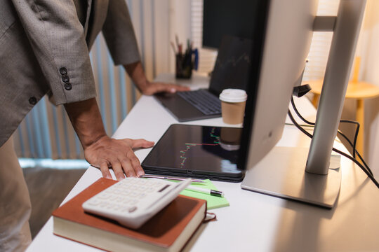 Professional trader analyzing stock market charts on laptop, tablet, and monitor while reviewing candlestick patterns, technical indicators, and market trends to support informed investment decisions.