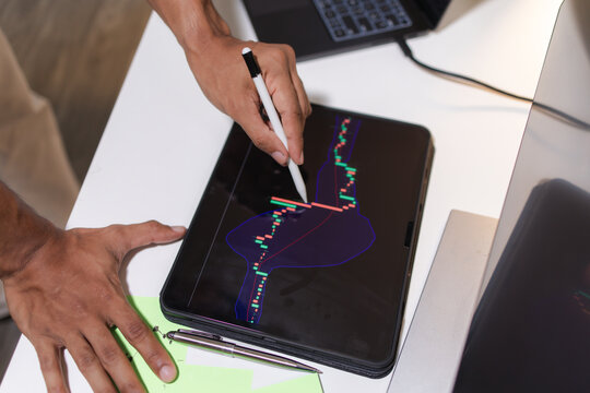Professional trader analyzing stock market charts on laptop, tablet, and monitor while reviewing candlestick patterns, technical indicators, and market trends to support informed investment decisions.