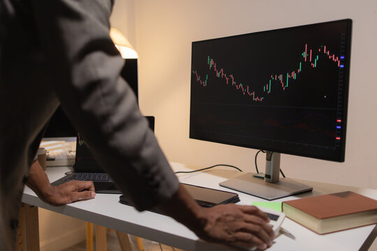 Professional financial analyst reviewing stock market charts across multiple screens using a tablet, laptop and calculator to evaluate price movements, technical indicators, and investment strategies.