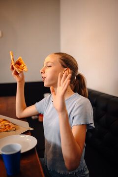 Teen girl eating pizza slice, talking and gesturing