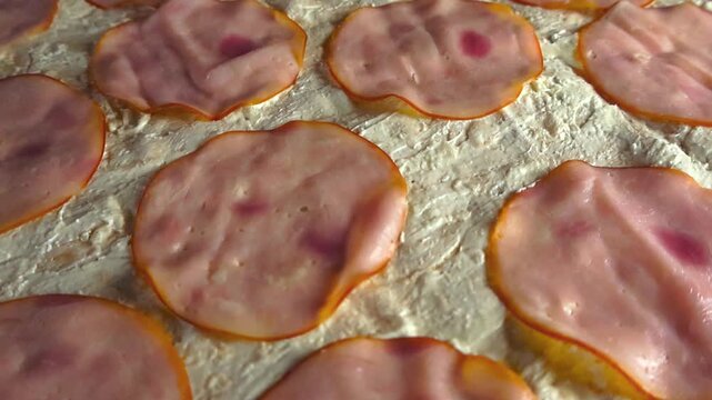 Delicious pink ham slices resting on a creamy white spread, covering a lavash flatbread in a mouthwatering close up view showing the texture and ingredients of an appetizing snack
