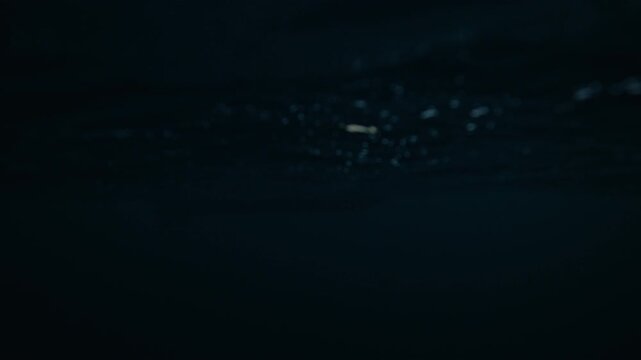 Rigid inflatable boat on Arctic sea at sunset with snowy mountains in Norway, backlit silhouette water level pov