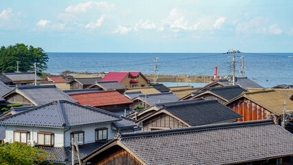 海辺に立ち並ぶ伝統的な瓦屋根の日本家屋 © ToYoPHoTo