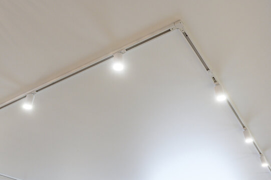 minimalist white ceiling features sleek aluminum track lighting system with adjustable spotlights, delivering clean directional illumination and modern architectural accent