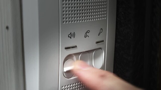 Intercom system buzzer, male finger presses volume button, answer and open button. Close up view of security device operation. Safety domestic apartment