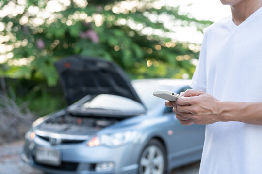 breakdown, broken car, repair. Man uses mobile phone check insurance premiums through application due to car accident . Find garage to get car fixed during country tour, waiting for help, emergency.