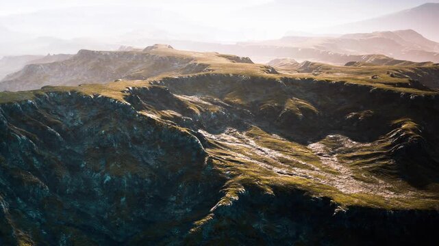 View of a mountain landscape with hills and valleys under sunlight. The scene captures the natural terrain and outlines of the rock formations in the morning light.