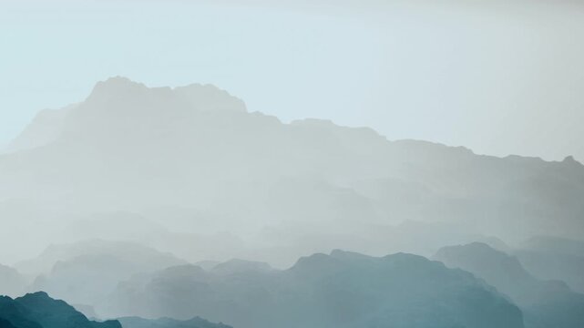 Layers of mountains can be seen shrouded in mist and fog during the early morning. The light creates a soft glow over the landscape, enhancing the view.