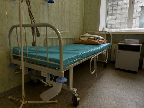 Interior of a hospital room with an empty bed.