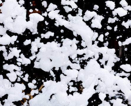 Snowflakes tumble through air against dark backdrop
