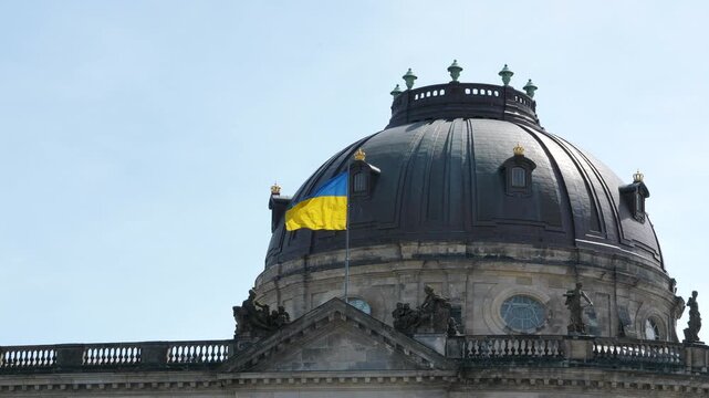 Ukraine flag waving next to dome of UNESCO Bode Art Museum in Berlin, telephoto