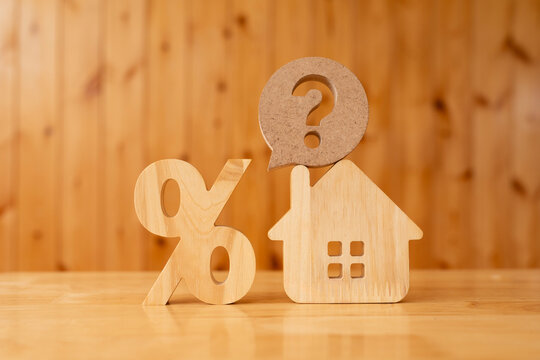 Mortgage interest rate inquiry and real estate loan concept with wooden percent symbol, house model and question mark bubble for property tax, refinancing cost and home buying advice.
