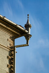 Vintage metal rain gutter downspout with decorative turret design on old building. Closeup of an antique ornate zinc drainage pipe with decorative turret element on the corner of historic castle wall © OlegD