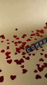 Conceptual video with the word communism written on black cubes surrounded by red heart shaped confetti, representing a controversial and complex political ideology on a neutral background