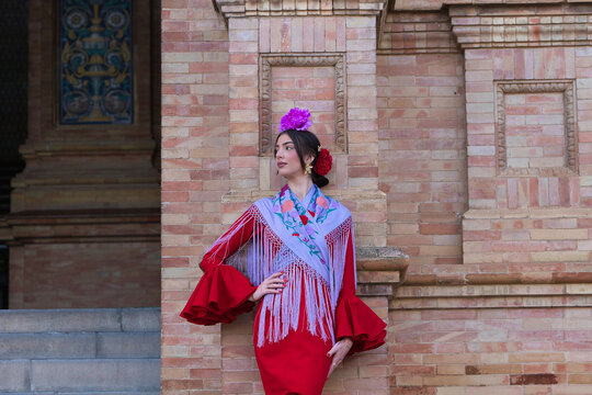 A beautiful woman dancing flamenco in a square in Seville, Spain. She is wearing a red ruffled dress and dances flamenco with great skill. Flamenco, a UNESCO Intangible Cultural Heritage.