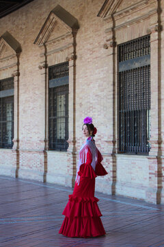 A beautiful woman dancing flamenco in a square in Seville, Spain. She is wearing a red ruffled dress and dances flamenco with great skill. Flamenco, a UNESCO Intangible Cultural Heritage.