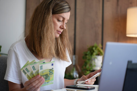 Woman counting euro cash and checking receipts at home