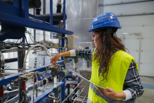 Woman technician checking industrial system during routine maintenance.