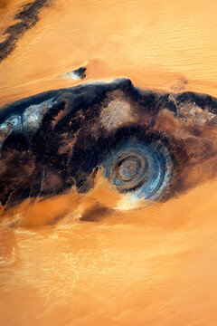 Eye of the Sahara, or Richat Structure, surrounded by golden desert sands in Mauritania, revealing its remarkable concentric geological rings from above.