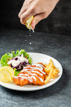 Fish and chips with hands inframe squishing a slice of lemon
