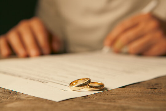 Wedding rings on a contract and a man signing a document