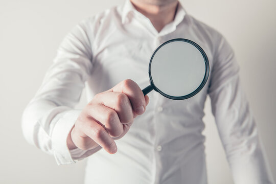 Man holding a magnifying glass in his hand. Focus on the magnifier.