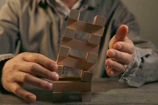 Businessman building a tower of wooden blocks. Concept of risk, management and development.
