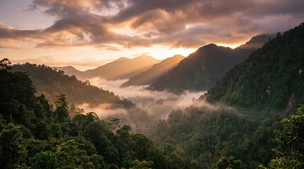 Obraz premium Breathtaking Sunrise Over Lush Tropical Rainforest Mountains with Morning Mist and Sun Rays Piercing Through the Valley Wilderness