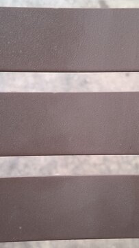 Close up view of horizontal brown metal slats on a bench.