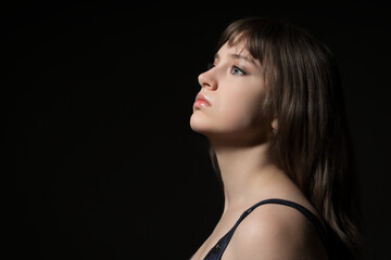 Fototapeta premium Portrait of a beautiful teenage girl posing in profile against a dark background