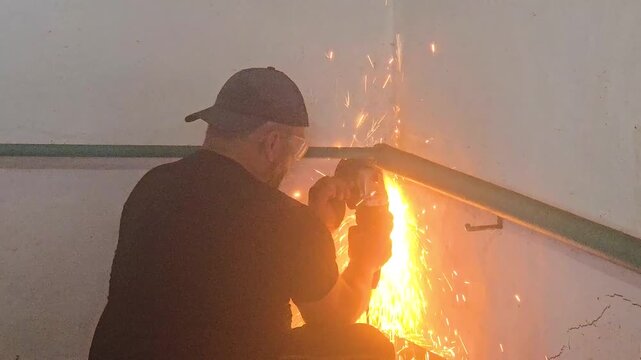 Man using an angle grinder to cut metal pipe during home renovation