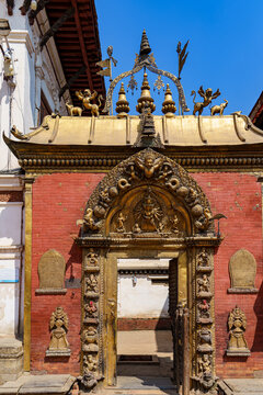 Nepal. Central. Kathmandu. Kathmandu Valley. Durbar Square. A gilded gateway surmounted by a tympanum depicting a deity surrounded by guardians and mythical creatures