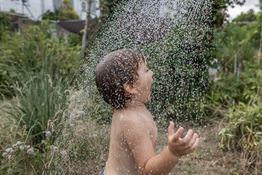 Boy playing with water in the backyard during a summer heatwave