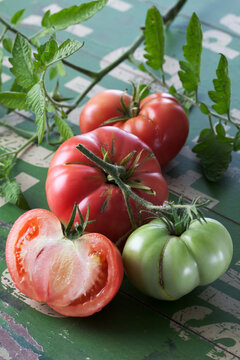 Whole and sliced Silesian raspberry tomatoes (Solanum lycopersicum), studio shot