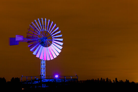 Germany, Nordrhein-Westfalen, Duisburg, Duisburg-Nord Landscape Park, View of illuminated wind mill of industrial plant at night