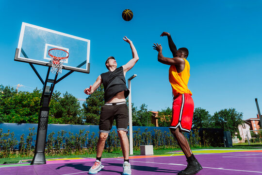 Men play a competitive basketball game on an outdoor court