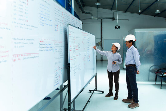 Female engineer explains wind farm strategy to a man indoors